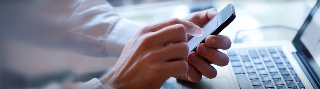 Pessoa a usar telemóvel junto a um computador